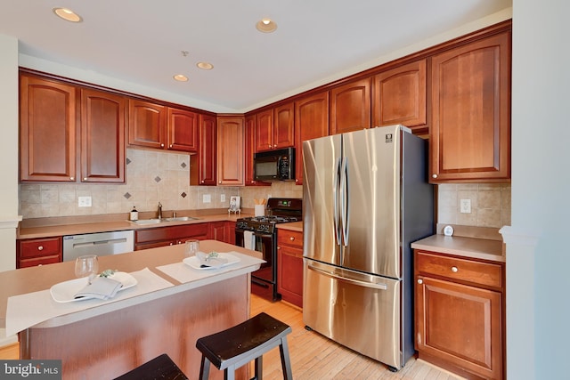 5012 Strawbridge Ter, Perry Hall, MD 21128 - kitchen with black appliances, a sink, backsplash, light wood finished floors, and a kitchen bar