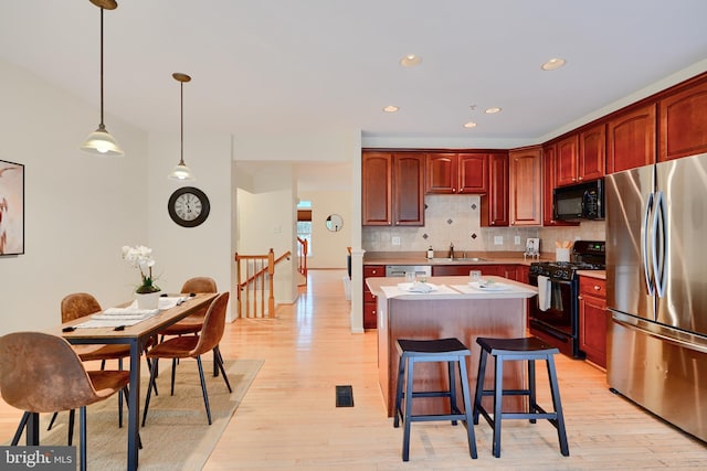 5012 Strawbridge Ter, Perry Hall, MD 21128 - kitchen featuring black appliances, a kitchen island, light wood-style floors, decorative backsplash, and recessed lighting