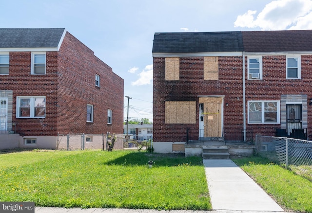 townhome / multi-family property featuring fence, roof with shingles, a front lawn, and brick siding