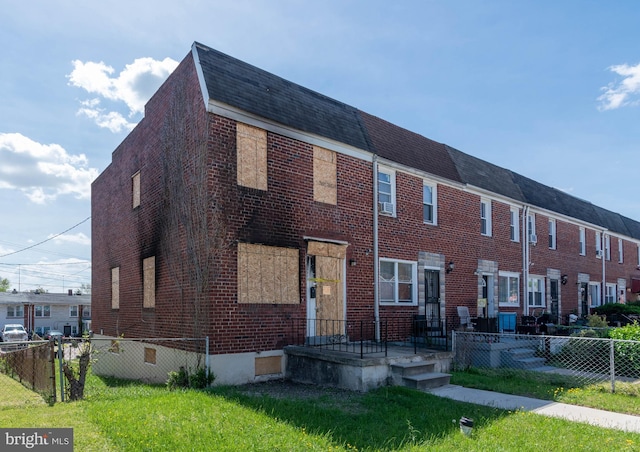 multi unit property with fence, a shingled roof, a front yard, and brick siding