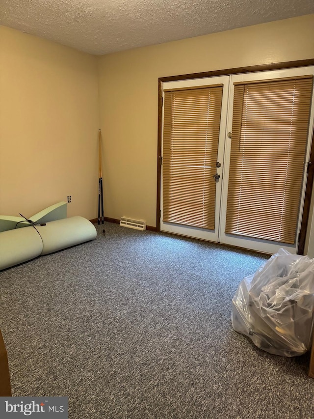 unfurnished room with carpet flooring, a textured ceiling, and visible vents