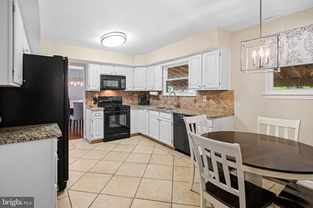 kitchen featuring an inviting chandelier, decorative backsplash, light tile patterned flooring, a sink, and black appliances