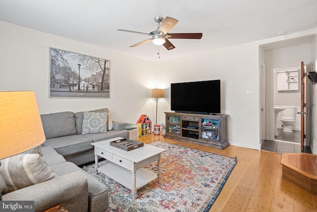 living room with baseboards, ceiling fan, and wood finished floors