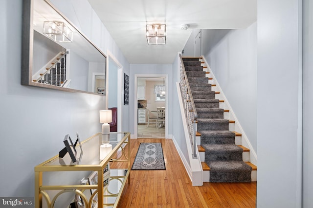 foyer entrance with stairway, baseboards, and wood finished floors