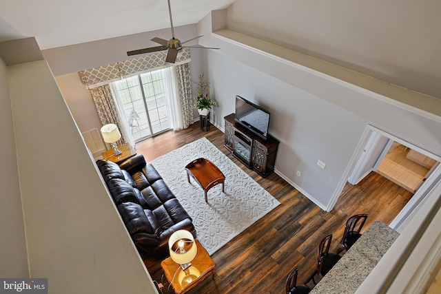 living area with baseboards, lofted ceiling, ceiling fan, and wood finished floors