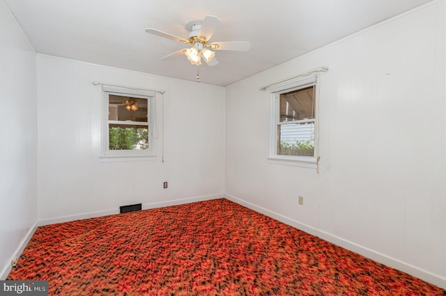 carpeted spare room featuring baseboards, plenty of natural light, ceiling fan, and visible vents