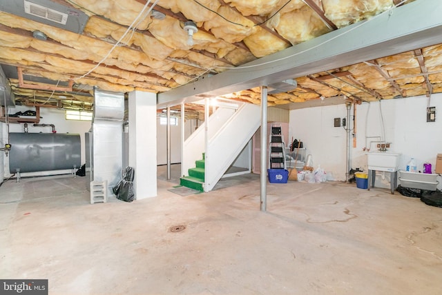 basement with visible vents, heating fuel, and stairs