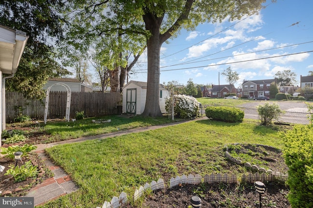 view of yard with an outdoor structure, fence, a storage shed, and a residential view