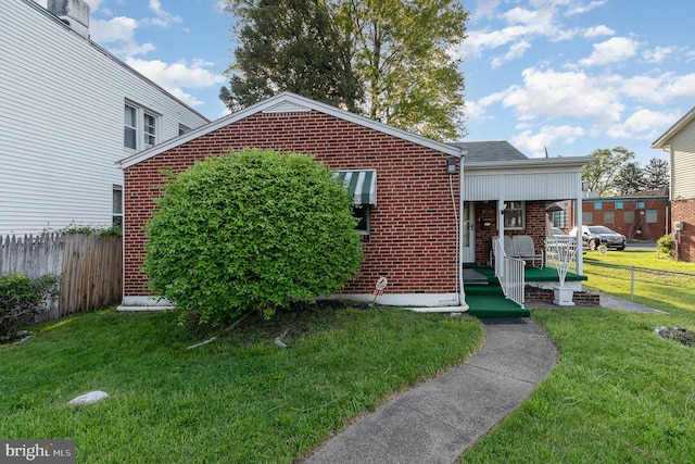 bungalow featuring fence, a front lawn, and brick siding