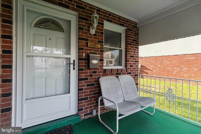 doorway to property with covered porch and brick siding