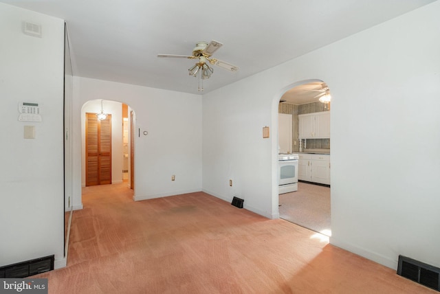 unfurnished room with arched walkways, ceiling fan, and visible vents