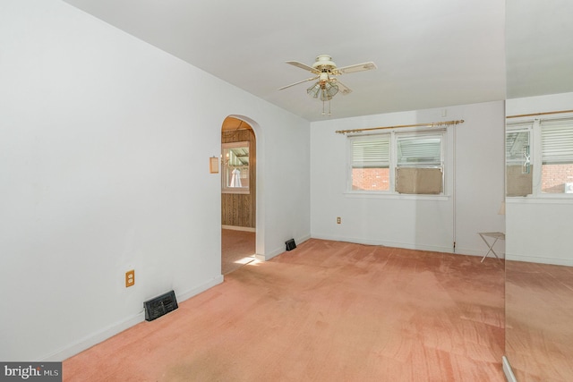 empty room with visible vents, arched walkways, ceiling fan, and a healthy amount of sunlight