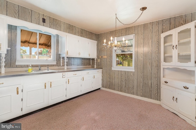 kitchen with an inviting chandelier, decorative light fixtures, light colored carpet, white cabinets, and glass insert cabinets