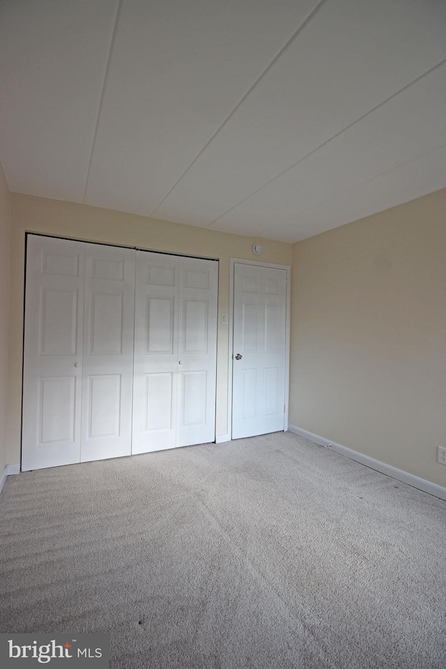 unfurnished bedroom with baseboards, carpet, and a closet