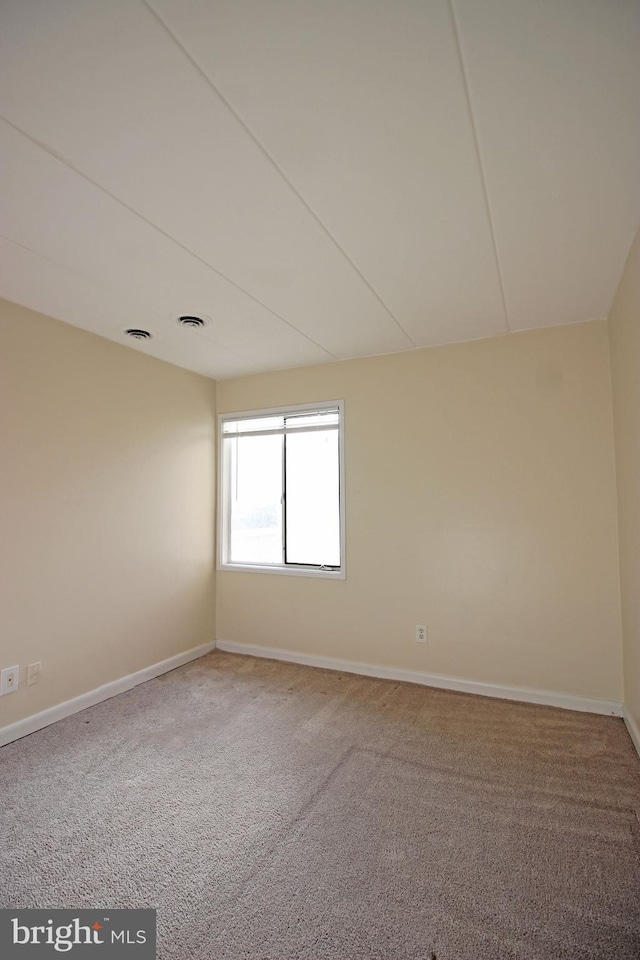 empty room featuring carpet floors, baseboards, and visible vents