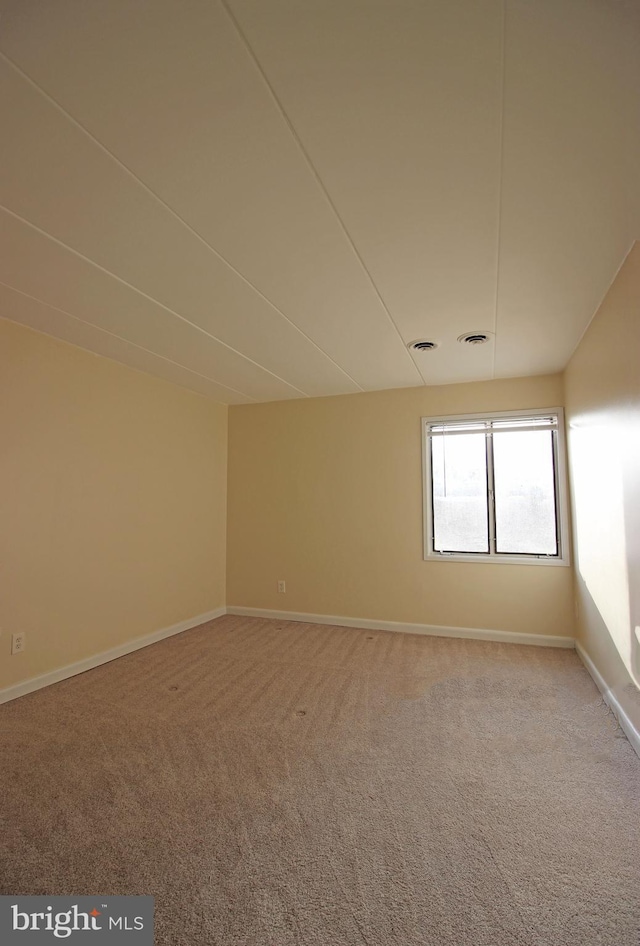 carpeted spare room featuring baseboards and visible vents