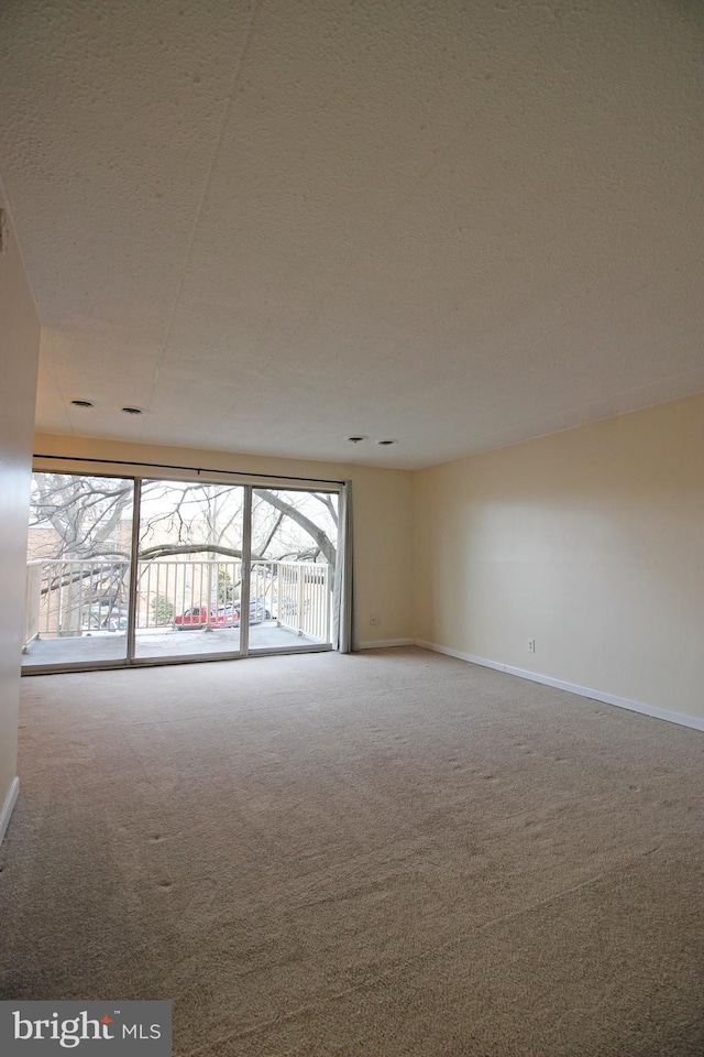 carpeted empty room with baseboards and a textured ceiling