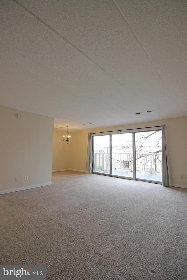 carpeted empty room with baseboards, a wealth of natural light, a textured ceiling, and a chandelier