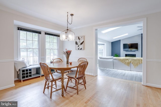 dining area featuring plenty of natural light, a skylight, lofted ceiling, a fireplace, and wood finished floors