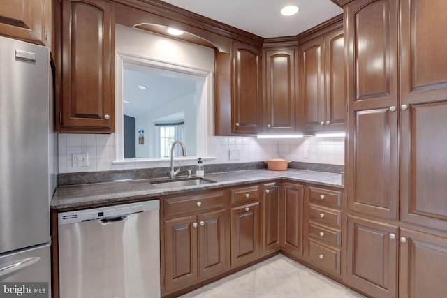 kitchen with appliances with stainless steel finishes, a sink, tasteful backsplash, light tile patterned flooring, and lofted ceiling