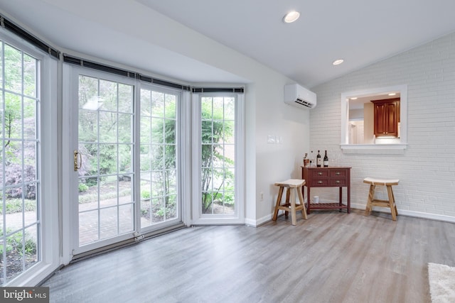 doorway featuring wood finished floors, baseboards, vaulted ceiling, healthy amount of natural light, and an AC wall unit