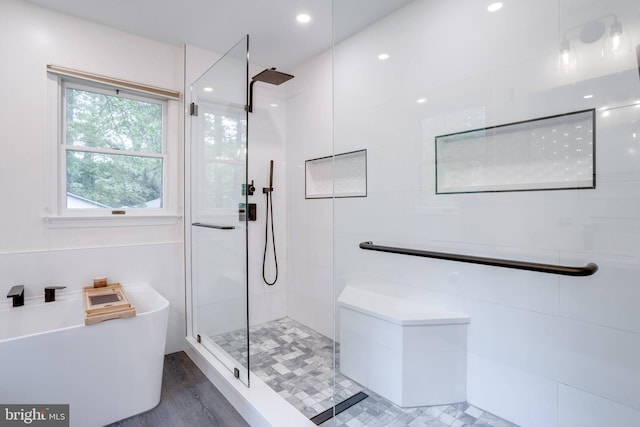 bathroom with a tile shower and a freestanding tub