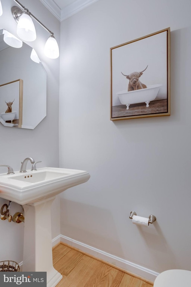 bathroom featuring ornamental molding, wood finished floors, baseboards, a sink, and toilet