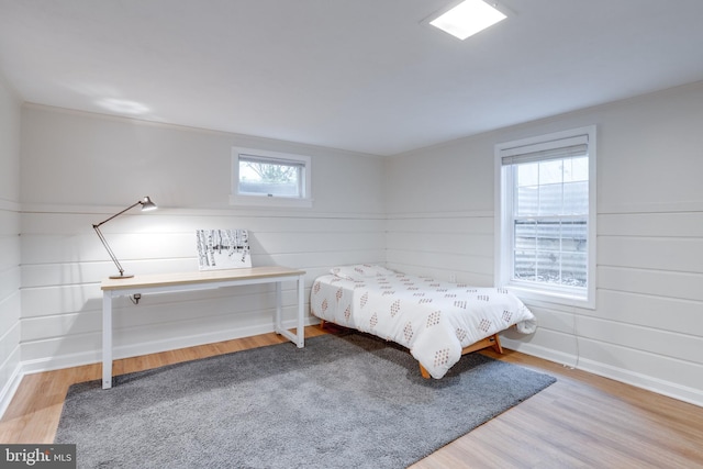bedroom with wood finished floors, ornamental molding, and baseboards