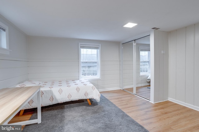 bedroom with wood finished floors, a closet, and baseboards