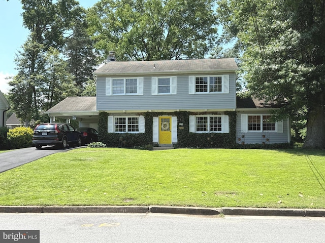 1109 Neal Dr, Alexandria, VA 22308 - colonial house with asphalt driveway, a front yard, an attached carport, and a chimney