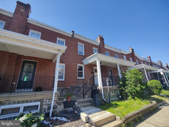 townhome / multi-family property with a porch and brick siding