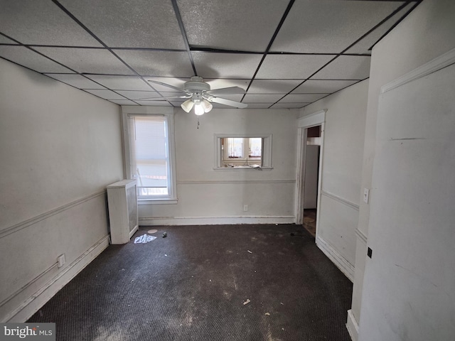 carpeted spare room with baseboards, a ceiling fan, and a paneled ceiling