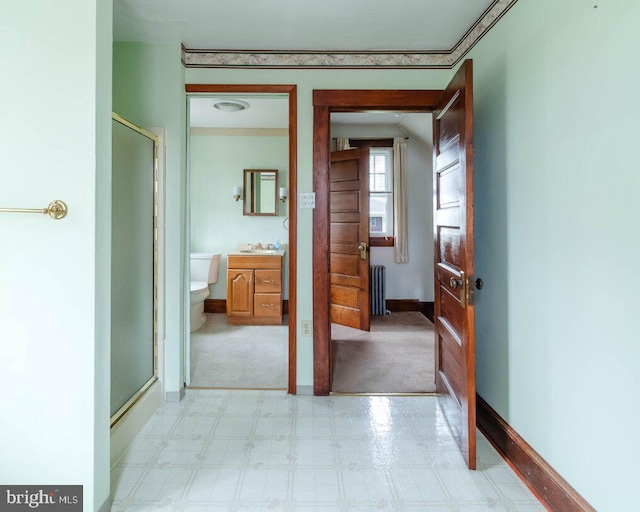 hall with a sink, light floors, baseboards, and radiator heating unit
