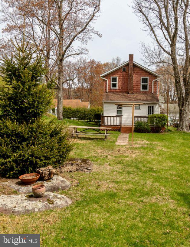 rear view of property featuring a yard, a chimney, and a wooden deck