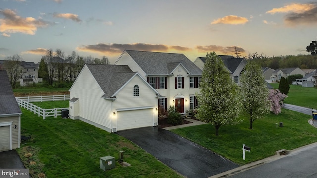 view of front facade featuring fence, a yard, driveway, and a residential view