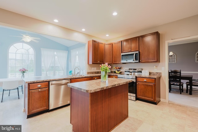 kitchen with a sink, light countertops, stainless steel appliances, a peninsula, and a kitchen island
