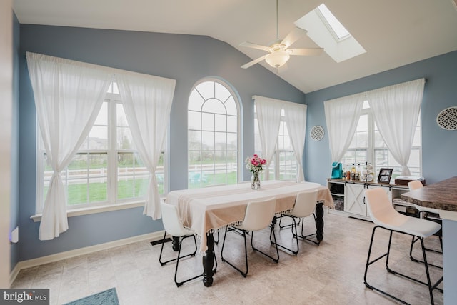 dining space with baseboards, lofted ceiling with skylight, a wealth of natural light, and ceiling fan