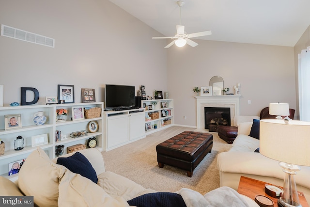 carpeted living room featuring ceiling fan, visible vents, high vaulted ceiling, baseboards, and a glass covered fireplace