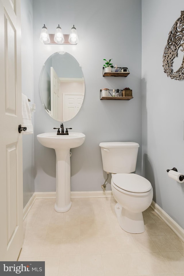 bathroom with toilet, baseboards, and tile patterned floors