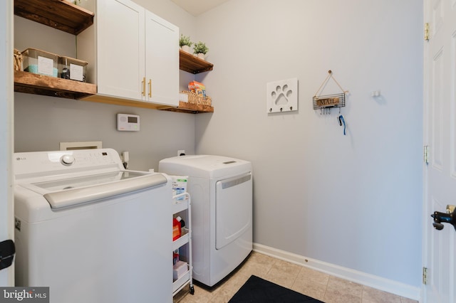 laundry area featuring cabinet space, baseboards, washing machine and dryer, and light tile patterned floors