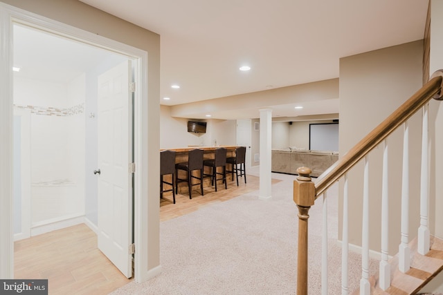 staircase featuring indoor wet bar, recessed lighting, baseboards, and wood finished floors