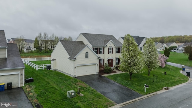 view of front of house with fence, a residential view, a front lawn, and aphalt driveway