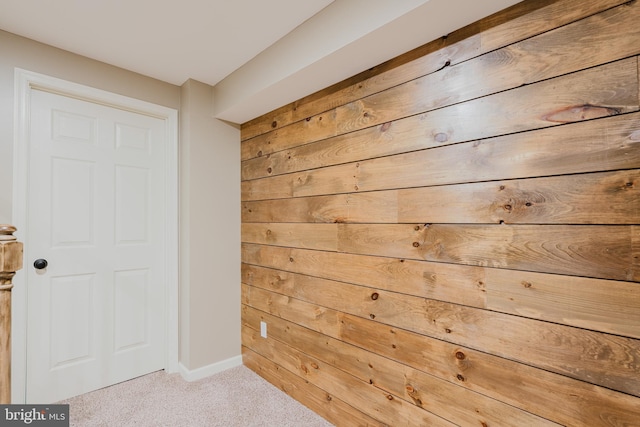 interior space featuring carpet floors, baseboards, and wood walls
