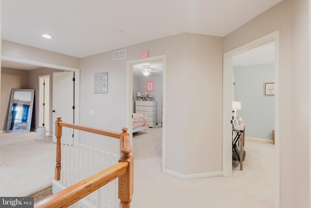 corridor with carpet floors, an upstairs landing, and visible vents