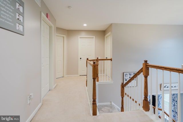 corridor with visible vents, baseboards, recessed lighting, carpet, and an upstairs landing