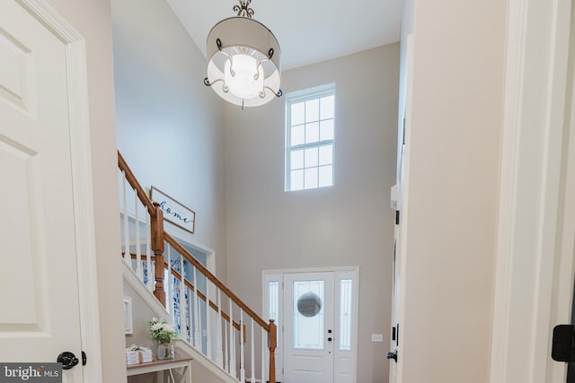 entrance foyer featuring stairs, a chandelier, and high vaulted ceiling