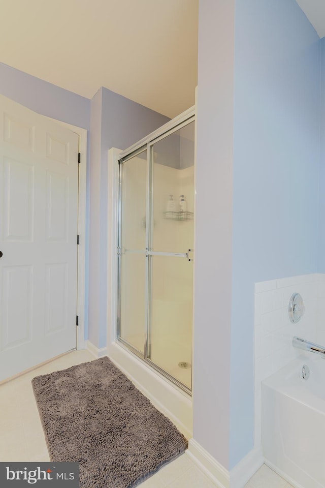 bathroom featuring baseboards, a shower stall, and a bath