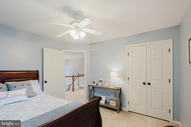 bedroom with visible vents, a ceiling fan, a closet, and light colored carpet