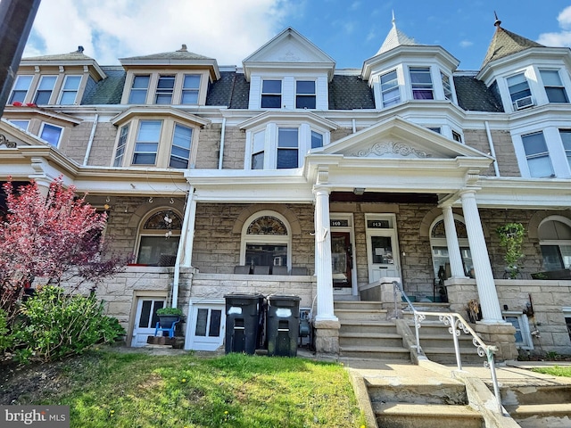 townhome / multi-family property with a porch and stone siding
