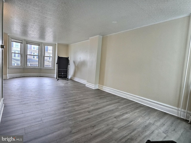 unfurnished living room featuring crown molding, baseboards, dark wood-style flooring, and a textured ceiling